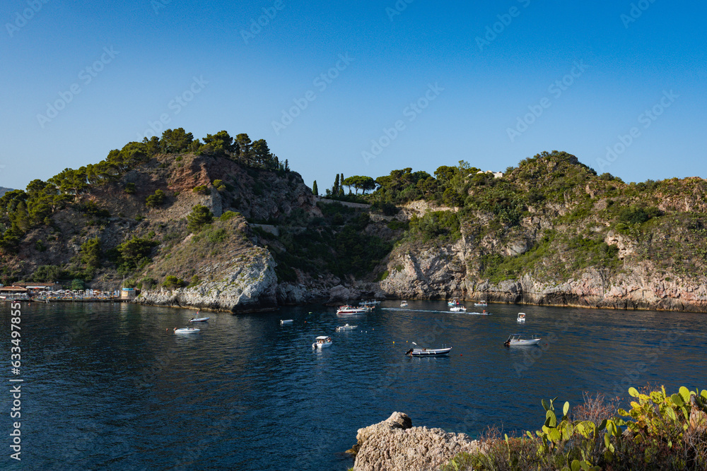 Aerial view of Taormina, Sicily in Italy. Tree covered hills and and water of bay with boats