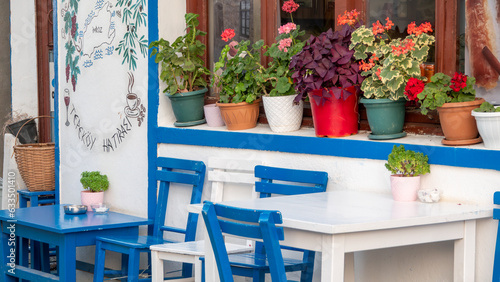 In front of the window of a house in Gökçeada Tepeköy, various flowers in pots, blue and white painted wooden table chairs. Tepekoy is a historic Greek  village in Gokceada island, Canakkale Turkey photo