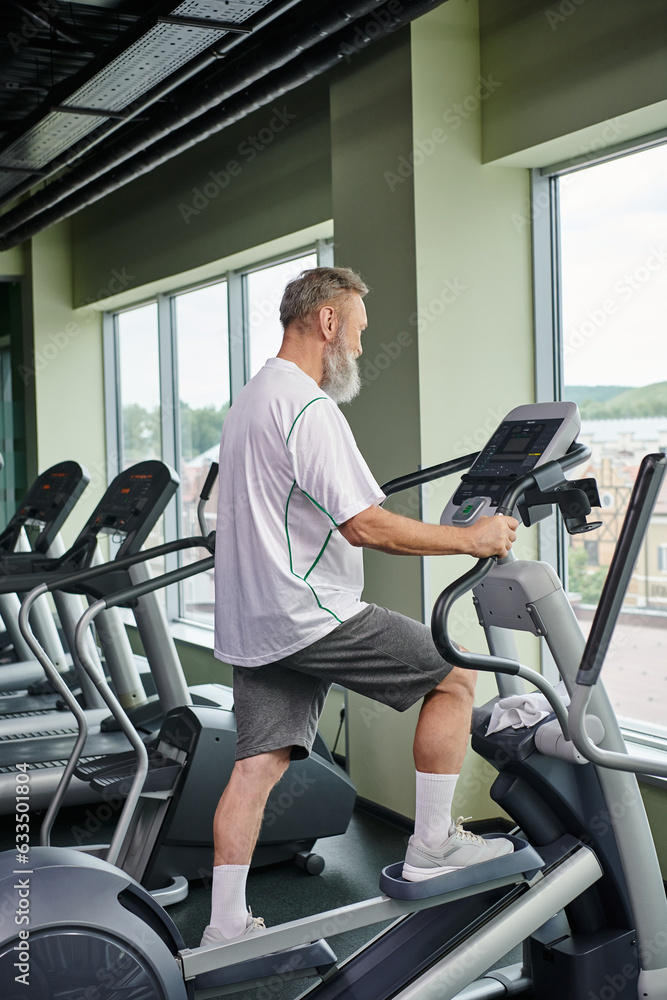 bearded senior man working out on stepper exercise machine, elderly in gym, active senior, sport bearded senior man working out on stepper exercise machine, elderly in gym, active senior, sport