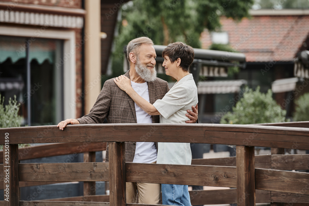 romantic senior couple standing together on wooden bridge and hugging each other, elderly love, bond romantic senior couple standing together on wooden bridge and hugging each other, elderly love, bond