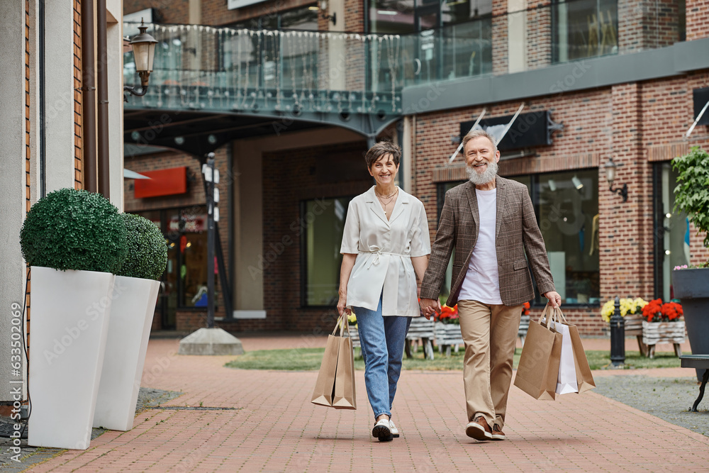 happy elderly couple having shopping, senior man and woman holding hands and walking on street happy elderly couple having shopping, senior man and woman holding hands and walking on street