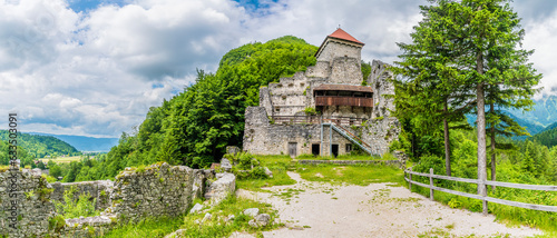 A panorama view towards the keep and tower of the Stone Castle ruins on the outskirts of the town of Begunje na Gorenjskem, Slovenia in summertime photo