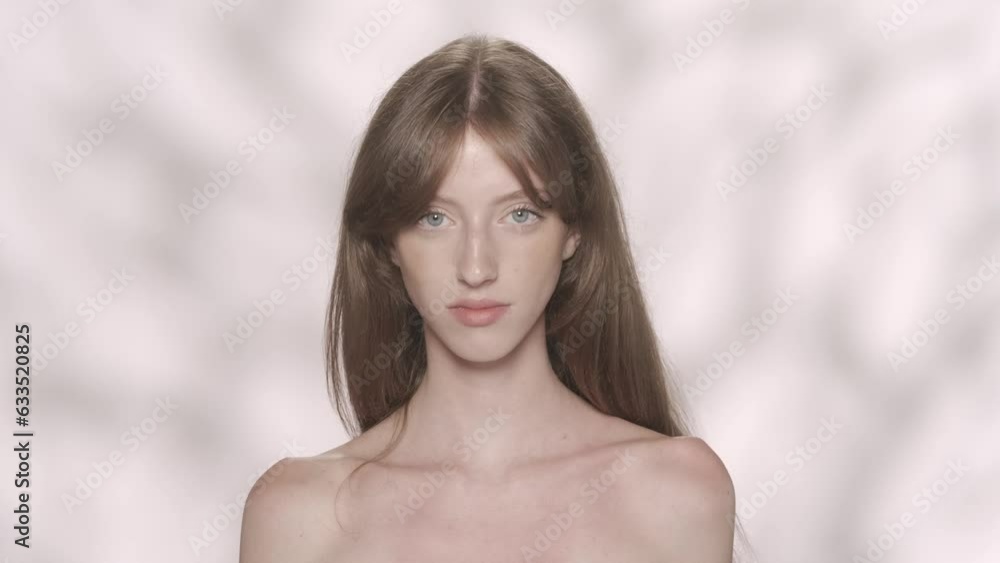 Attractive girl with soft makeup and blue eyes fixing her long shiny hair and looking at the camera HDR BT2020 HLG Material. Attractive girl with soft makeup and blue eyes fixing her long shiny hair and looking at the camera HDR BT2020 HLG Material.