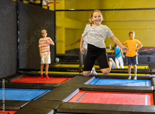 Playful girl jumping on trampoline at playground indoor