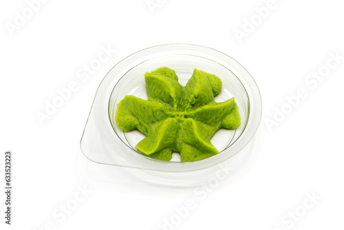 Transparent bowl with green wasabi sauce isolated on white background.