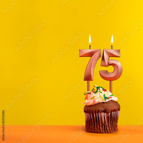 Number 75 birthday candle - Celebration on yellow background photo