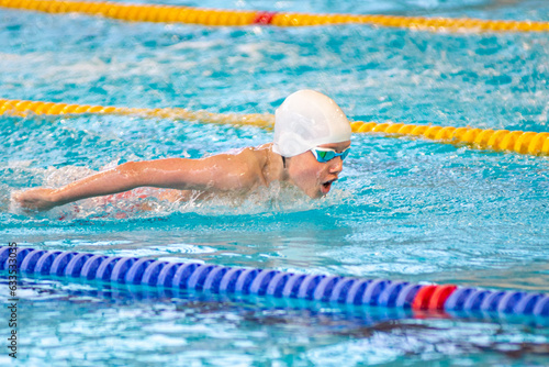 Swimmer boy swims butterfly swimming style in the pool