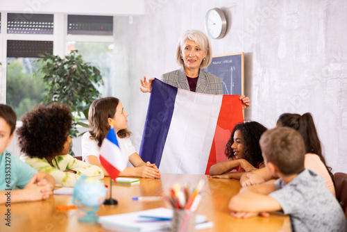 at evening geography lesson, elderly teacher tells attentive students about France