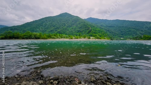 Timelapse: view of mountains with green trees, surface of the flowing river Chorokh and grey cloudy sky - overcast. Georgian landscape near Batumi in Georgia. Summer, nature and time lapse concept photo