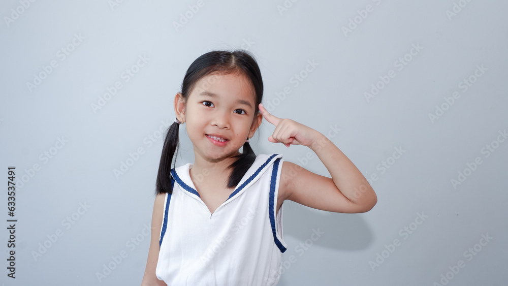 beautiful asian child wearing white dress point at her head. beautiful asian child wearing white dress point at her head.
