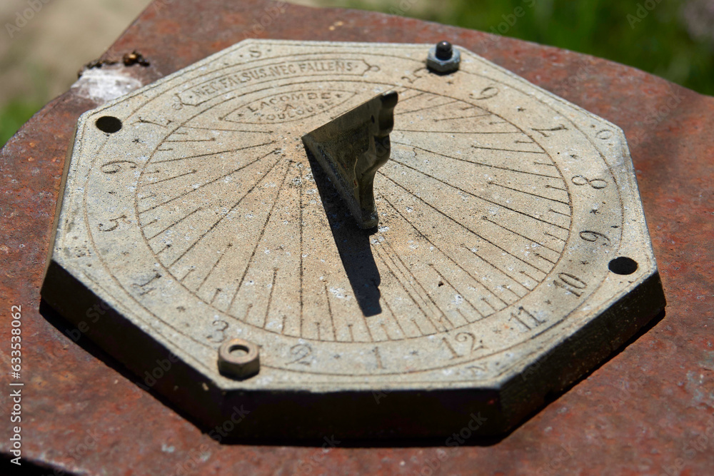 Old metal sundial with clear light showing the time in the middle of the day