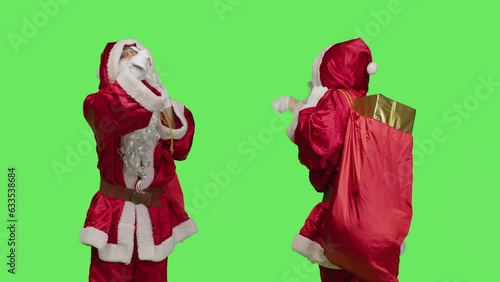 Saint nick bandmaster chief in costume accompany professional orchestra as choir musician, standing over greenscreen. Santa claus with gifts bag playing band music, musical conductor.