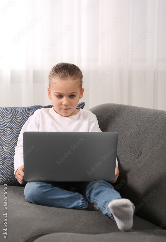Little girl using laptop on sofa at home. Internet addiction Little girl using laptop on sofa at home. Internet addiction