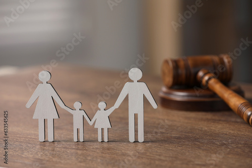 Family law. Figure of parents with children and gavel on wooden table, space for text photo