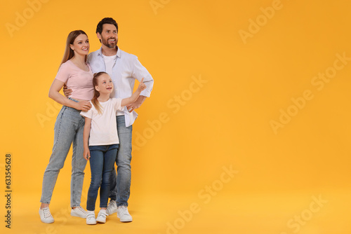Happy family on orange background, space for text © New Africa