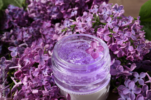 Jar of cosmetic product and lilac flowers on table