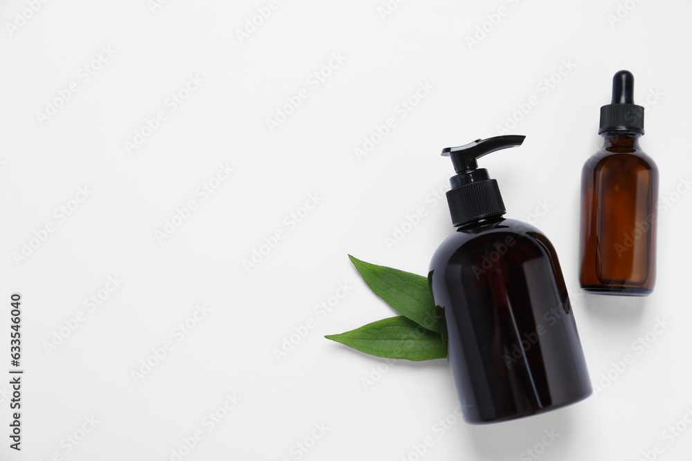 Bottles with different cosmetic products and green leaves on white background, flat lay. Space for text Bottles with different cosmetic products and green leaves on white background, flat lay. Space for text