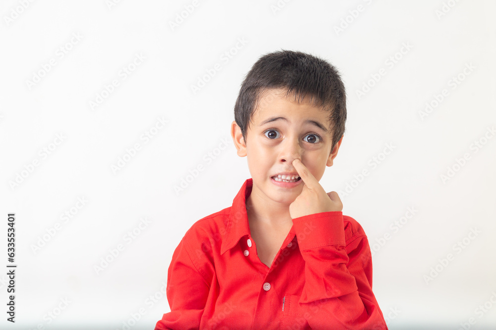 .cute boy making a sly face..A cute looking boy in a red shirt making a slimy face in white room..Studio portrait, concept health with white background. .funny face.. .cute boy making a sly face..A cute looking boy in a red shirt making a slimy face in white room..Studio portrait, concept health with white background. .funny face..