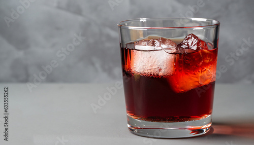 Glass of Americano Alcohol cocktail with red vermouth, bitter, soda water and ice cubes on grey background. Side view.