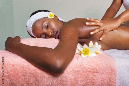 african woman at a spa centre laying on the bed , having a massage and skin moisturize, pampering session