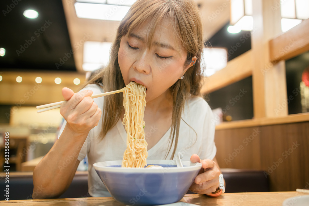 Asian women enjoy eating ramen noodles in japanese restaurant Asian women enjoy eating ramen noodles in japanese restaurant