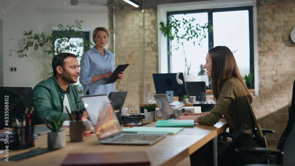 Female ceo checking employees work in company office. Woman looking at laptop Female ceo checking employees work in company office. Woman looking at laptop