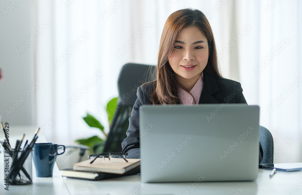 Young asian female office worker sitting in bright office and working on computer laptop. Young asian female office worker sitting in bright office and working on computer laptop.