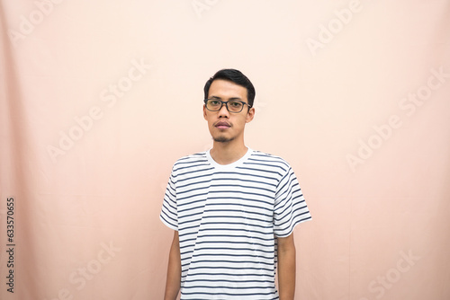 Asian man in glasses wearing casual striped t-shirt, standing pose, smiling and serious.