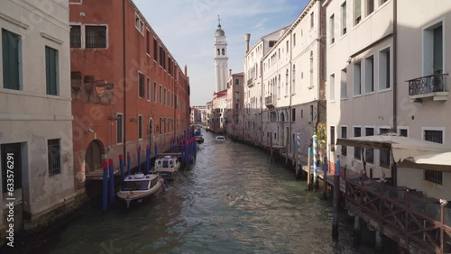 Small canal in Venezia italy during sunny day with Towerbell as background photo