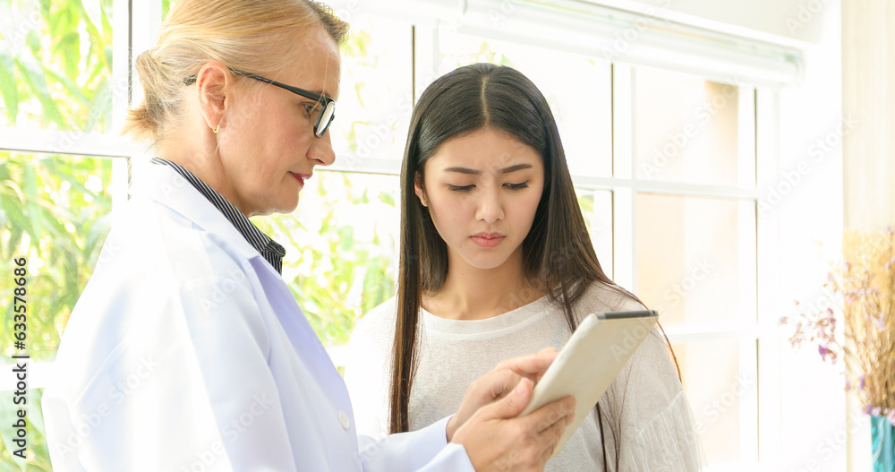 Asian woman patient sitting with doctor about her illness and showing x-ray results Asian woman patient sitting with doctor about her illness and showing x-ray results