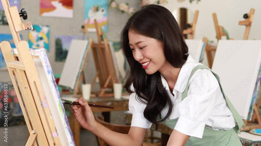 Asian woman painting on canvas, she is an artist who creates watercolor painting, art painting. Concept artist design drawing art on canvas paper. Asian woman painting on canvas, she is an artist who creates watercolor painting, art painting. Concept artist design drawing art on canvas paper.