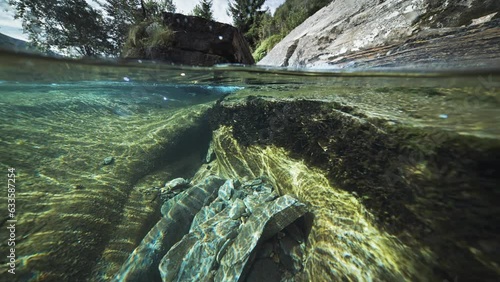 Mesmerizing over-under view of a shallow river with rocky shores and clear water. photo