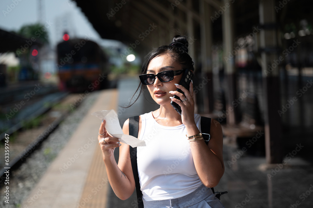 Young beautiful woman wear sunglasses using smartphone at  Hua Lamphong station in Bangkok, Thailand