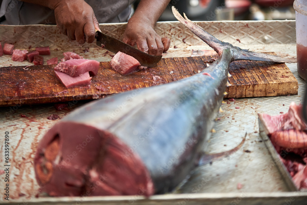 A resident of Kerala cuts freshly caught tuna on a chopping board