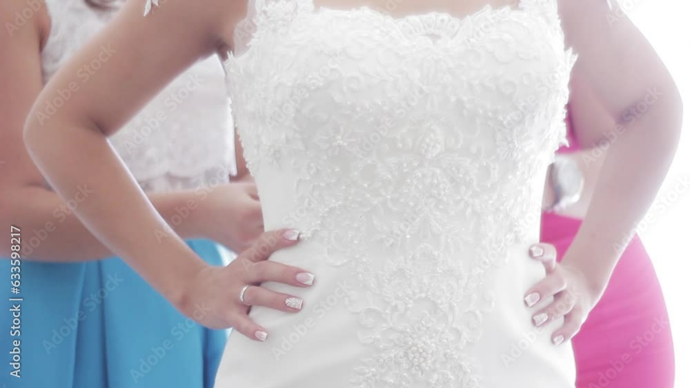 Close-up of the rear of the wedding dress. Bridesmaids help to get dressed. Girls bridesmaids dress bride dress tying Close-up of the rear of the wedding dress. Bridesmaids help to get dressed. Girls bridesmaids dress bride dress tying