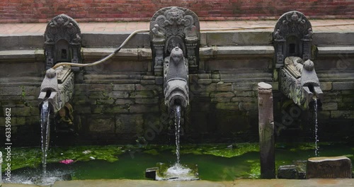 Traditional Stone Carved Watertaps at Patan Durbar Square UNESCO World Heritage site Nepal. Three water taps and continuous water flow. Drinking water for Tourists Natural resource 4K photo