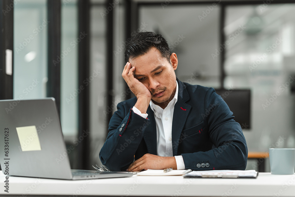 Asian businessman of Indian descent overworked in the office feeling stressed and disappointed. Asian businessman of Indian descent overworked in the office feeling stressed and disappointed.