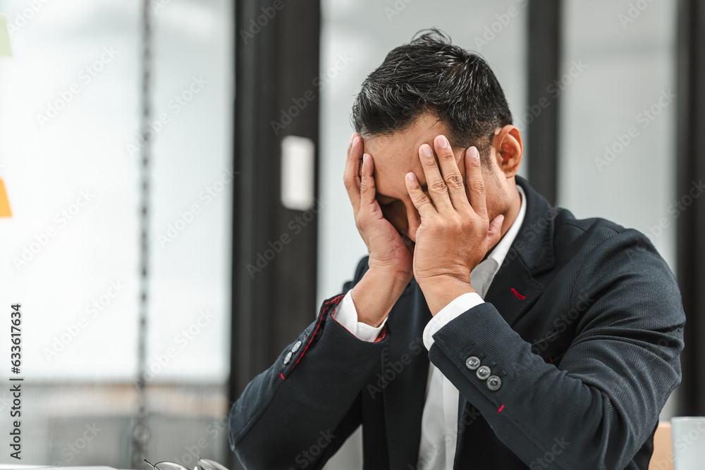 Asian businessman of Indian descent overworked in the office feeling stressed and disappointed. Asian businessman of Indian descent overworked in the office feeling stressed and disappointed.