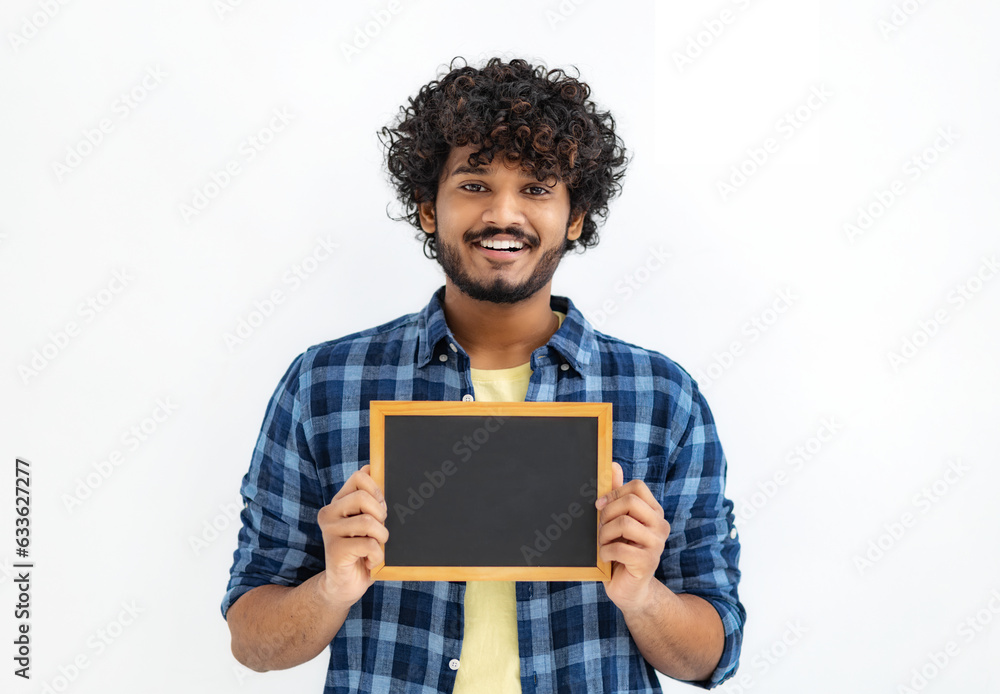 Happy Asian man with curly hair holds a small empty chalkboard looks at the camera and smiles friendly standing on a white background Happy Asian man with curly hair holds a small empty chalkboard looks at the camera and smiles friendly standing on a white background