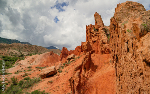 Dramatic clouds and blue sky over red sandy canyons in Kyrgyzstan.Unusual geological landscape.