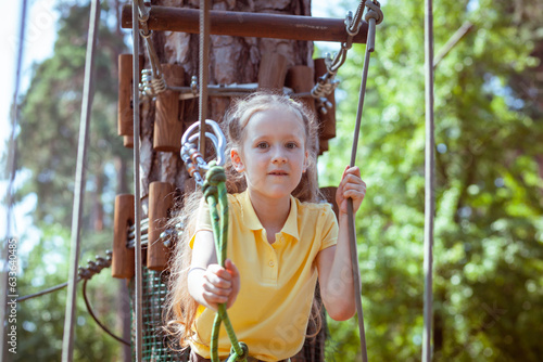 Child in a forest adventure park made of ropes. Children's outdoor climbing entertainment center. Playground for children and sports with a cableway. Sports suspended rope trainer.