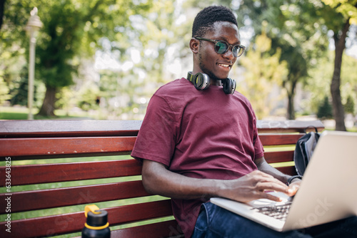 Young man sitting in the park and using laptop