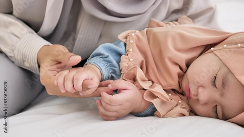 Soothing Bond, In tender moments, a mother tends to her holding hand sleeping baby girl, fostering a strong bond of protection, care, and boundless love. Muslim, 6-month-old baby girl. slow motion