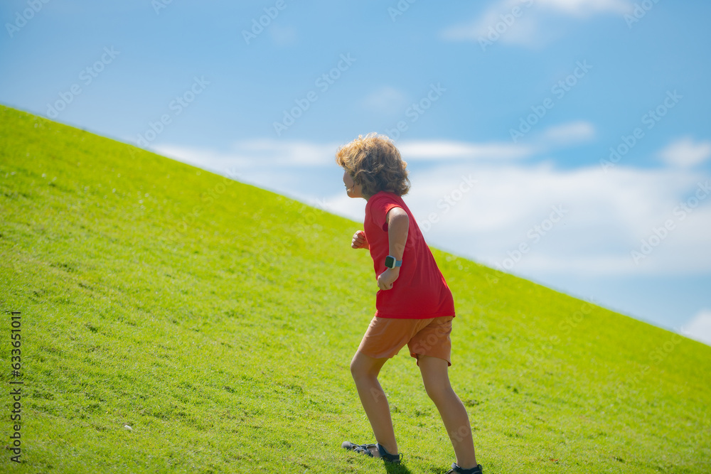 Sporty kid boy running on green grass and blue sky. Kid boy running outdoor. Sport for children. Runner kids race in park. Sporty kid boy running on green grass and blue sky. Kid boy running outdoor. Sport for children. Runner kids race in park.