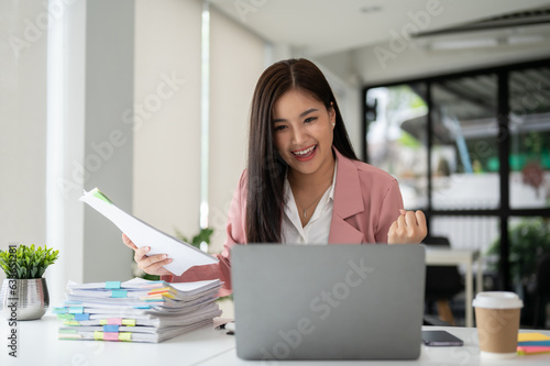 A cheerful Asian businesswoman looking at her laptop screen with an excited face