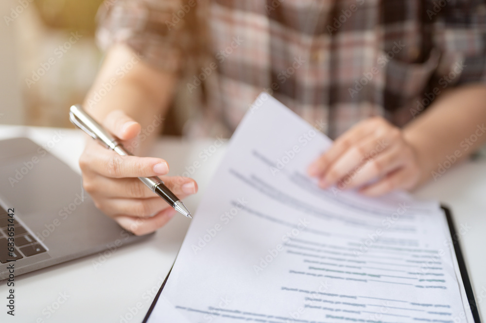 Close-up image of a woman reading contract and signing her signature on a contract agreement Close-up image of a woman reading contract and signing her signature on a contract agreement