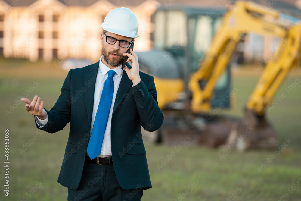 Construction builder investor. Man investor in front of construction site. Successful handsome man standing at modern home building construction. Portrait of midlle aged investor in suit and helmet. Construction builder investor. Man investor in front of construction site. Successful handsome man standing at modern home building construction. Portrait of midlle aged investor in suit and helmet.