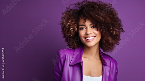 Curly haired young woman smiles on vibrant purple backdrop combining white and purple hues