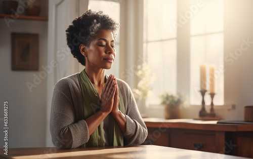 Black african american dark-skinned senior woman praying to God or doing meditation alone at dawn at home
