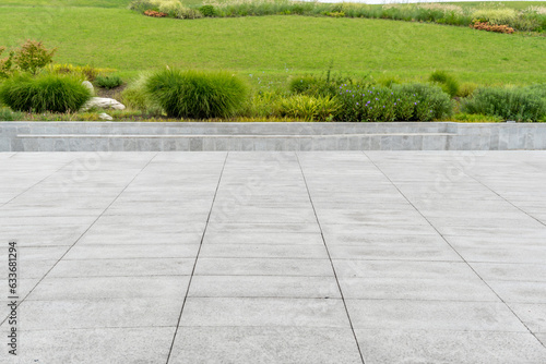 empty concrete floor in front of meadow in the public park of modern city.
